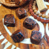 Brown mahogany obsidian stones with black specks on a wooden surface