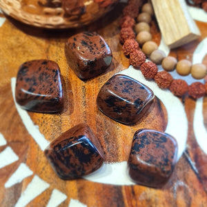 Brown mahogany obsidian stones with black specks on a wooden surface