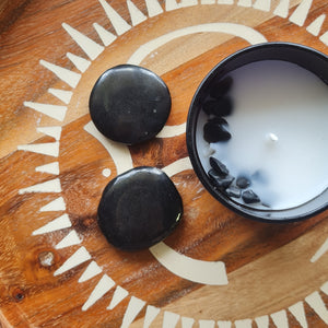 Black shungite flat stones on a wooden surface with a decorative pattern