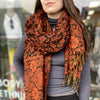 Person wearing an orange and black patterned scarf in a store setting