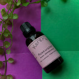 A bottle of Kereru Natural Products Rosewater on a dual-tone background with green and purple paper. The label has the brand name and product name written on it.